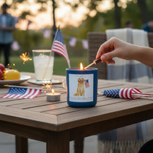 Load image into Gallery viewer, LocalCandleCo patriotic Golden Retriever citronella candle being lit on an outdoor patio table with American flags.
